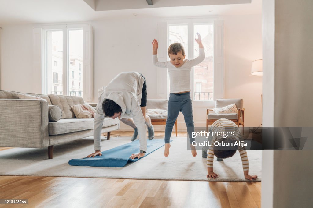 Père avec des enfants faisant l’exercice à la maison