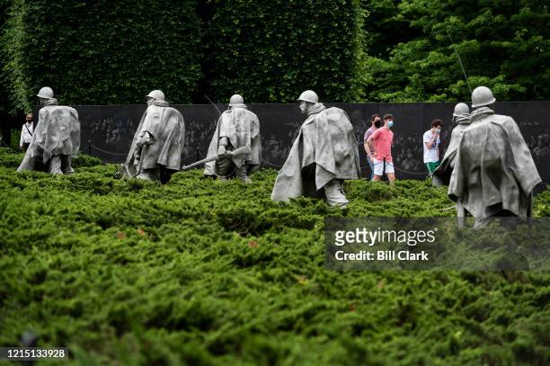 Visitors wearing face masks walks through the Korean War Veterans Memorial on Memorial Day, Monday, May 25, 2020.