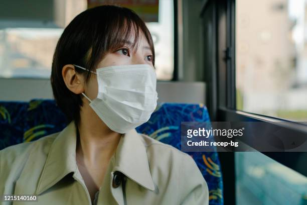 businesswoman commuting by bus while wearing surgical mask - japan covid stock pictures, royalty-free photos & images