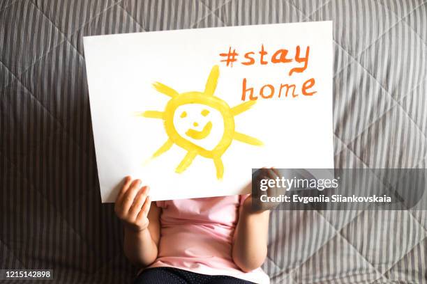 close up of child's hands holding a piece of paper with text stay home and sun. - holding kid hands stock pictures, royalty-free photos & images