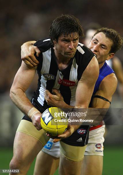 Leigh Brown of the Magpies handballs whilst being tackled during the round 22 AFL match between the Collingwood Magpies and the Brisbane Lions at...