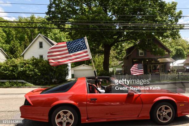Person waves an American flag as they participate in a car parade for Memorial Day on May 25, 2020 in Phillipstown, New York. Participants of the car...