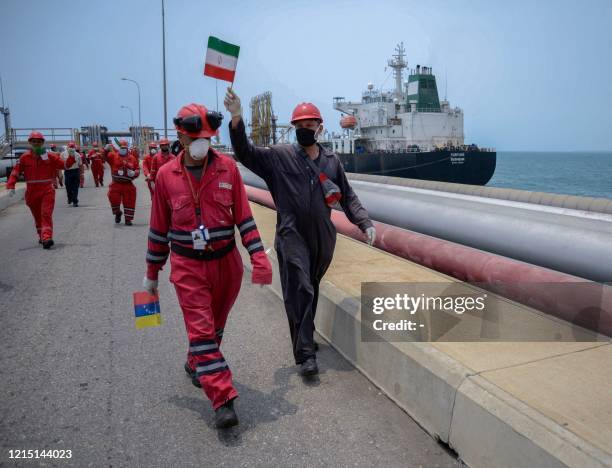 Worker of the Venezuelan state oil company PDVSA waves an Iranian flag as the Iranian-flagged oil tanker Fortune docks at the El Palito refinery in...