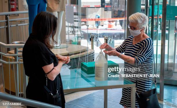 An employee at the Simons store explains health safety procedures to a customer, both wearing facemasks, on Sainte-Catherine Street, in Montreal,...