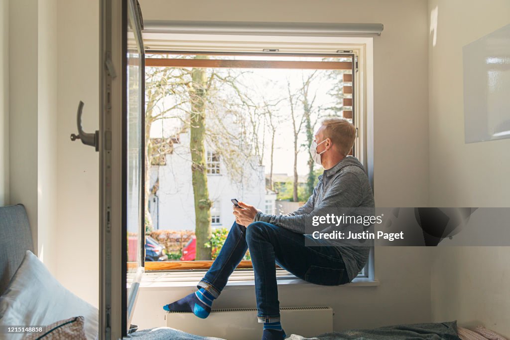 Man with mask looking out of window