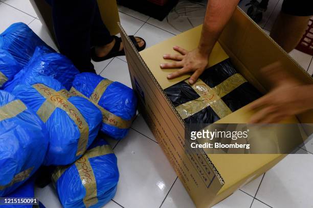 Workers pack personal protective equipment in a box at a production facility in Kuala Lumpur, Malaysia, on Thursday, May 21, 2020. Malaysia reported...