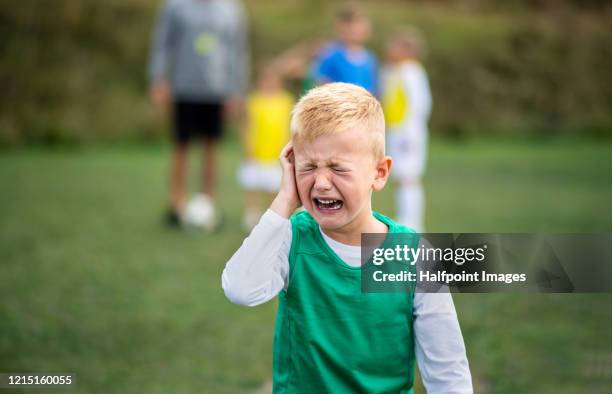 small boy in pain crying outdoors on football pitch. - head coach stockfoto's en -beelden