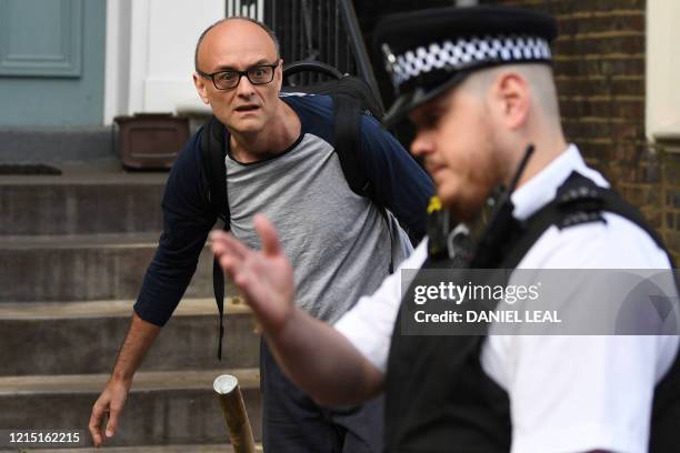 Police officer points the way to Number 10 special advisor Dominic Cummings as he leaves his residence in north London on May 26, 2020. - British...