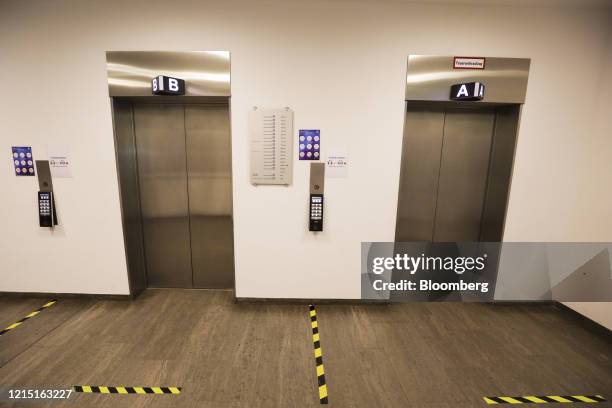 Social distancing floor markers sit beside elevator doors in the Deutsche Bank AG offices in Eschborn, Germany, on Monday, May 25, 2020. The trickle...