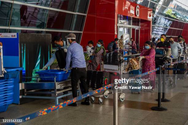 Travelers put their luggage in X-ray machine before at the drop-off point before entering Terminal 3 of the Indira Gandhi International Airport, as...