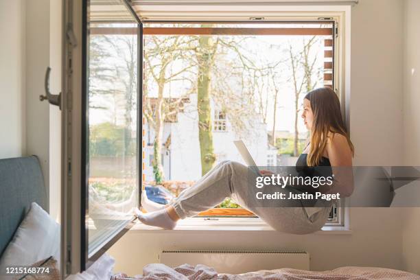 teenage girl using laptop - windowframe stock-fotos und bilder