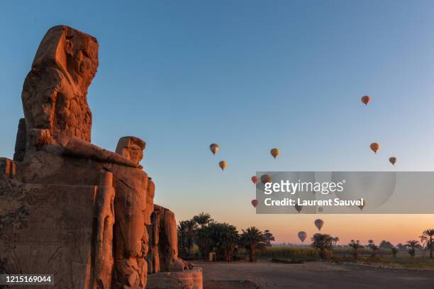 colossi of memnon at dawn with hot air balloons in the sky, luxor, nile valley, egypt - colossi of memnon stock pictures, royalty-free photos & images