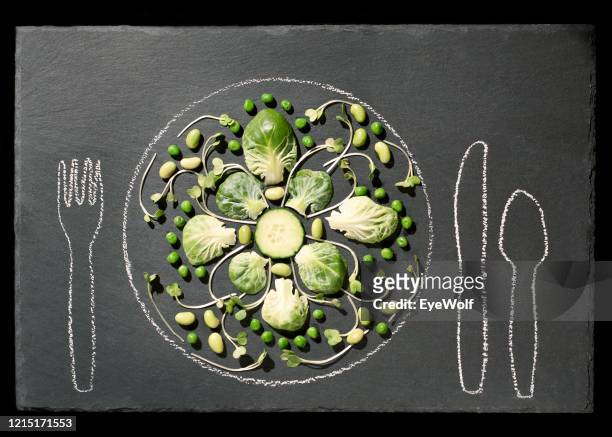 overhead shot of brussel sprouts laid out in a mandala with a plate and silverware drawn in chalk - wolf only white background stock pictures, royalty-free photos & images