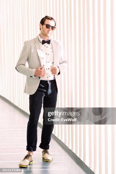 portrait of a man walking down a hallway, wearing a blazer and a bow tie - full frontal stock-fotos und bilder