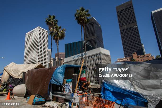 Homeless man fixes his bike outside his tent next to the 110 Freeway, during the novel Coronavirus, COVID-19, pandemic in Los Angeles California on...