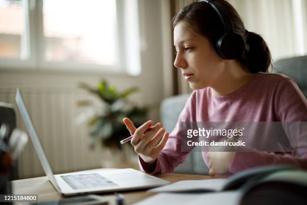 adolescente chica con auriculares que tienen clase de la escuela en línea en casa - teen computer fotografías e imágenes de stock