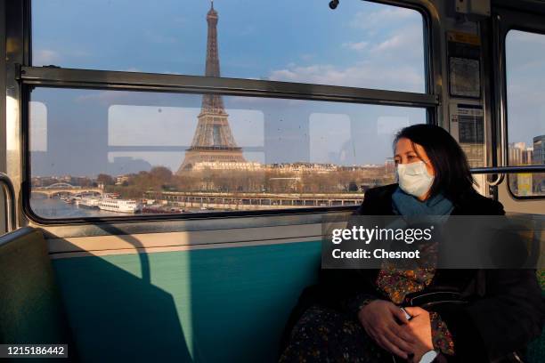 Passenger wearing a protective mask is seen in a subway train as she passes in front the Eiffel tower during the Coronavirus epidemic on March 27,...