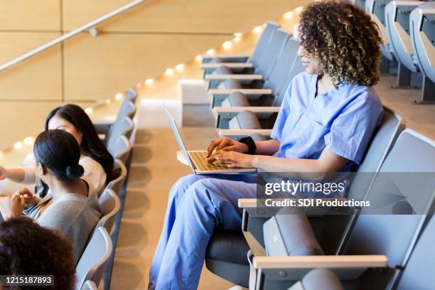 female student sitting alone in classroom takes notes on laptop - community college stock pictures, royalty-free photos & images