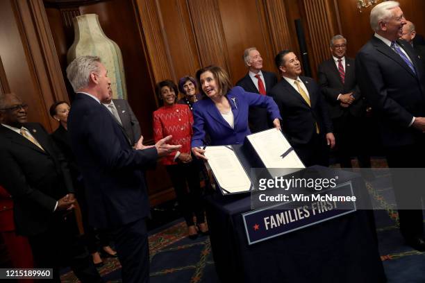 Speaker of the House Nancy Pelosi , surrounded by a bipartisan group of members of the House, shows off the stimulus bill known as the CARES Act...