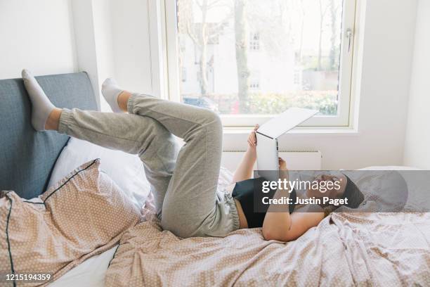 teenage girl using laptop on bed - pantaloni di tuta foto e immagini stock