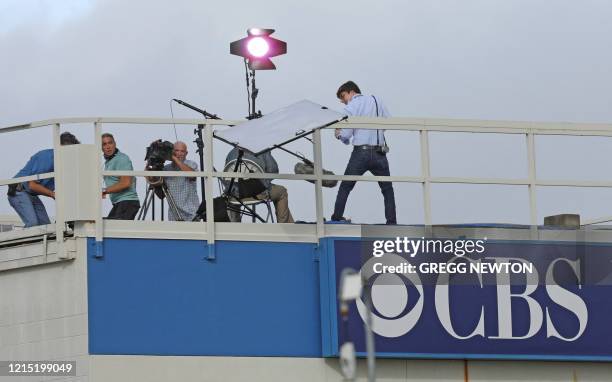 News crew looks on as a reflector topples over from the wind while preparing to broadcast at the Kennedy Space Center in Florida on May 26, 2020....