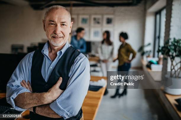 positive elderly leader with crossed arms - baby boomer millennial stock pictures, royalty-free photos & images