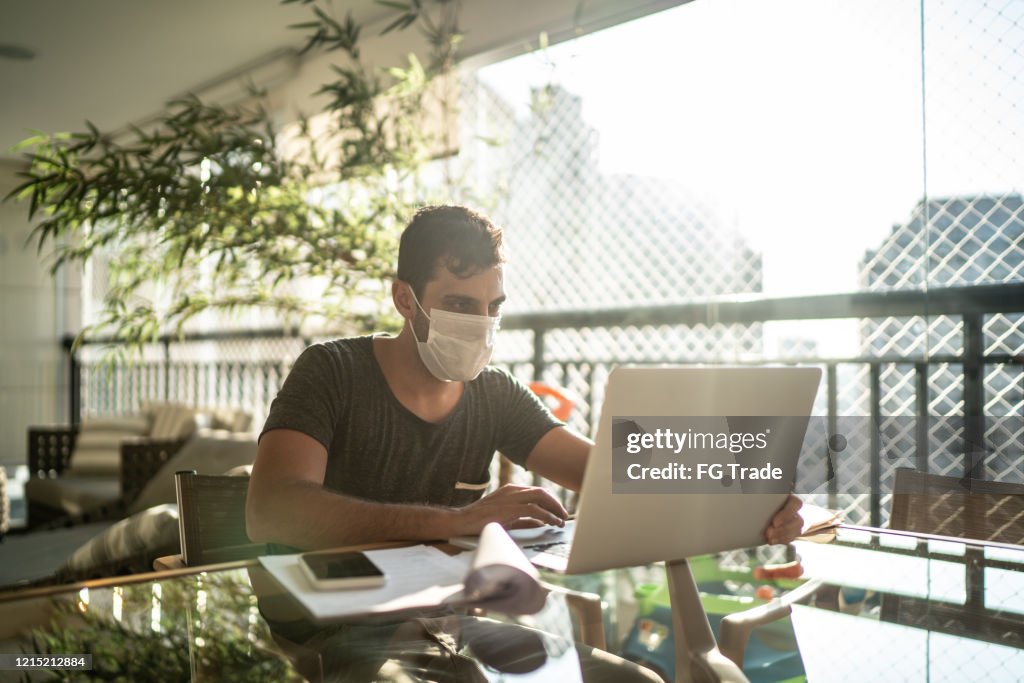 Young businessman working at home with face mask