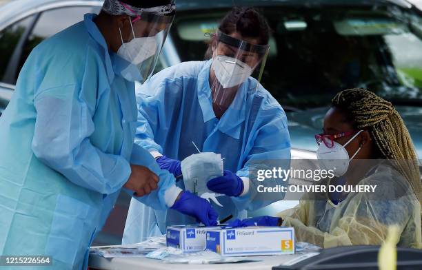 Health workers prepare to give people free COVID-19 tests without needing to show ID, doctor's note or symptoms at a drive-through and walk up...