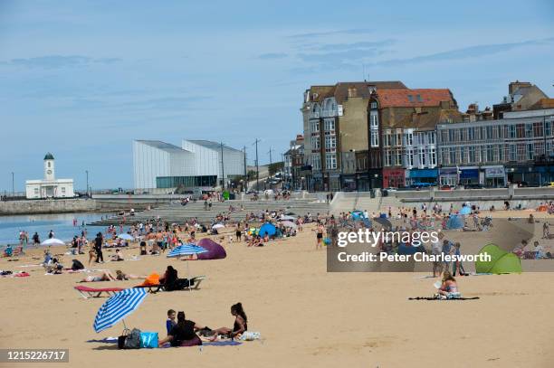 People and families on the beach sunbathing, swimming, playing and generally enjoying the fine sunshine in one of England's oldest seaside resorts,...