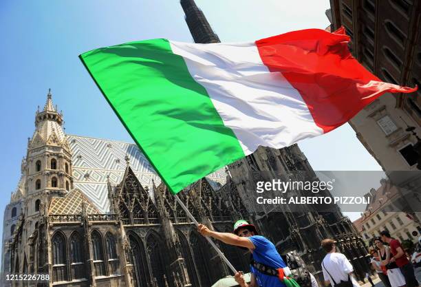 Supporter of the Italian national football team waves an Italian flag in front of St. Stephen's Cathedral in central Vienna on June 22 hours before...
