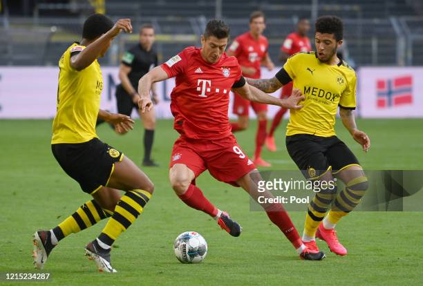 Robert Lewandowski of Bayern Munich is challenged by Jadon Sancho and Manuel Akanji of Borussia Dortmund during the Bundesliga match between Borussia...