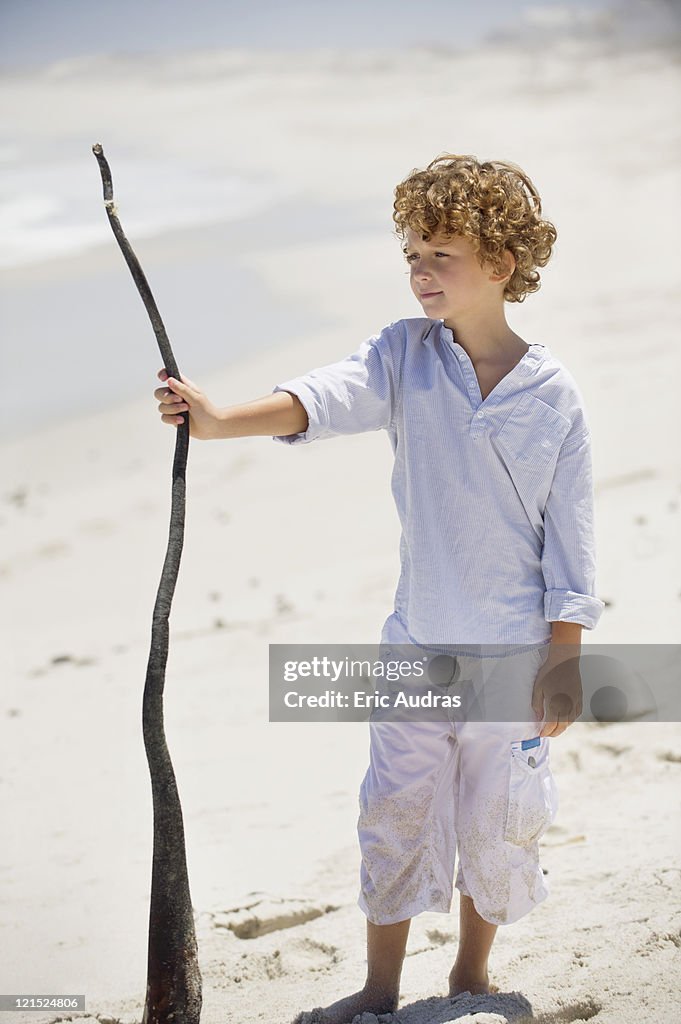 Boy holding a wooden stick on the beach