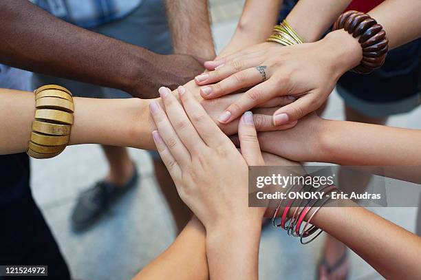 close-up of human hands stacked upon one another - hand stack stock pictures, royalty-free photos & images