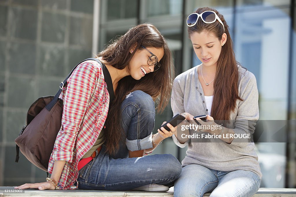 Two young female friends reading messages
