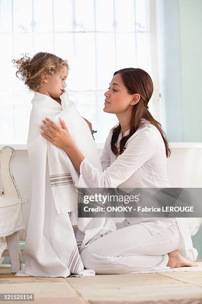 woman wrapping her daughter in towel after the bath - mother daughter towel fotografías e imágenes de stock