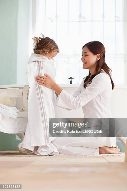 woman wrapping her daughter in towel after the bath - mother daughter towel fotografías e imágenes de stock