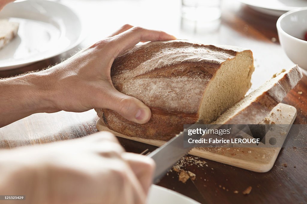 Close-up of a person's hand cutting bread