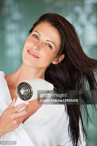 portrait of a woman drying her hair with a hair dryer - föhn stock-fotos und bilder