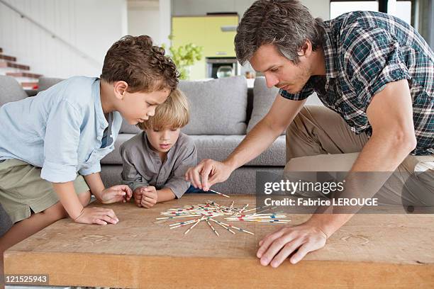 man playing pick up sticks with his sons - mikado stock pictures, royalty-free photos & images