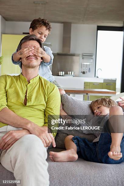 boy covering his father's eyes by his brother  - augen zuhalten stock-fotos und bilder