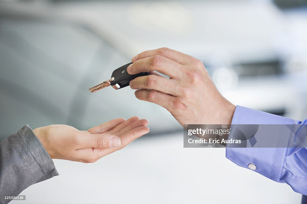 Salesman handing car key to woman