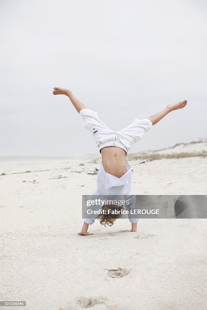 Boy doing handstand on beach