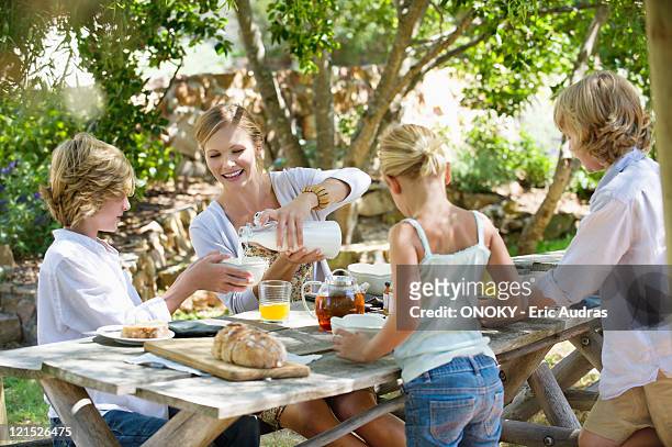 family having food at front or back yard - moeder kind zes melk stockfoto's en -beelden