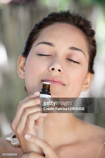 young woman smelling aromatherapy oil - aromatherapy oil stockfoto's en -beelden