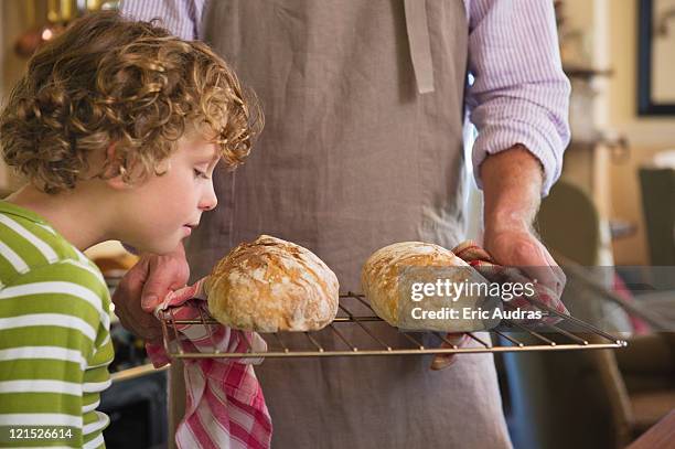 cute little boy smelling baked bread in father's hand - baked goods stockfoto's en -beelden