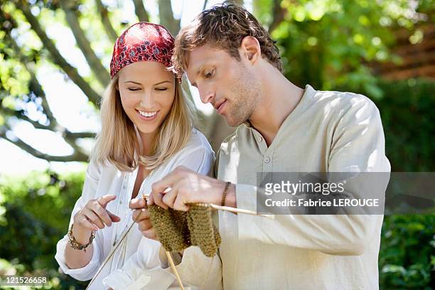 young couple knitting together and smiling - man knitting stock pictures, royalty-free photos & images
