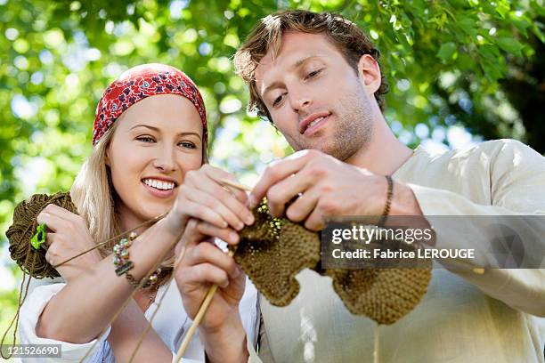 young couple knitting together and smiling - knit stockfoto's en -beelden