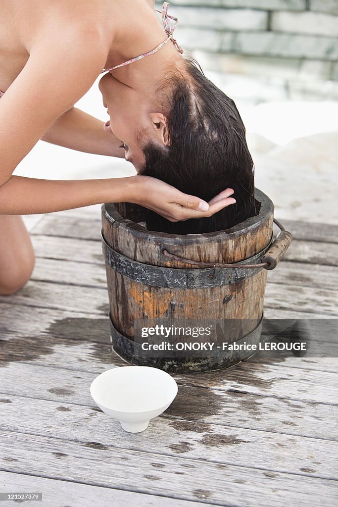 Woman washing hair into a bucket