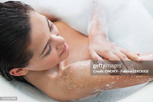 beautiful young woman taking bubble bath - badzout stockfoto's en -beelden