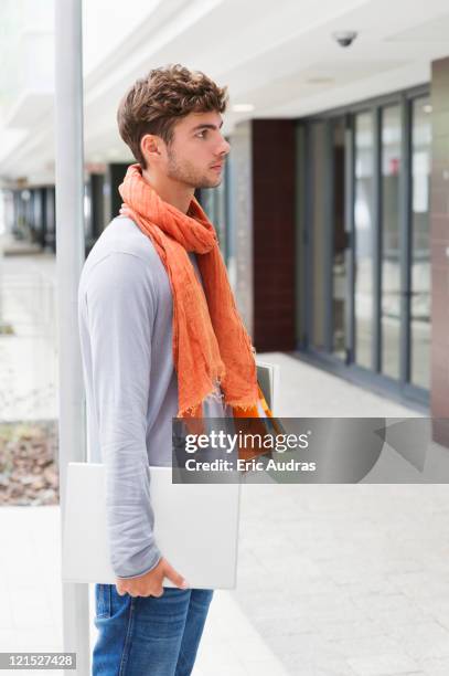 side profile of a man standing with books and laptop in hands - unter dem arm stock-fotos und bilder